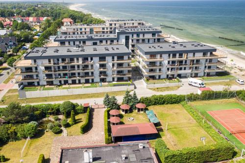 濟夫努夫的住宿－Apartament LUCKY 7 Gardenia Seaside，享有一座带网球场的大型建筑的空中景致