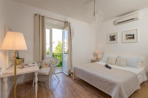 a white bedroom with a bed and a desk and a window at Ortenca Apartment in Dubrovnik