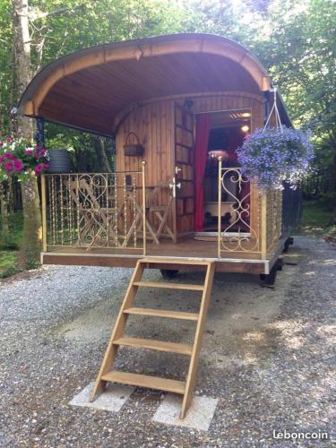 a small wooden house with a ladder and flowers at ROULOTTE - LE DOMAINE DES ECREVISSES in Saint-Florent-sur-Cher