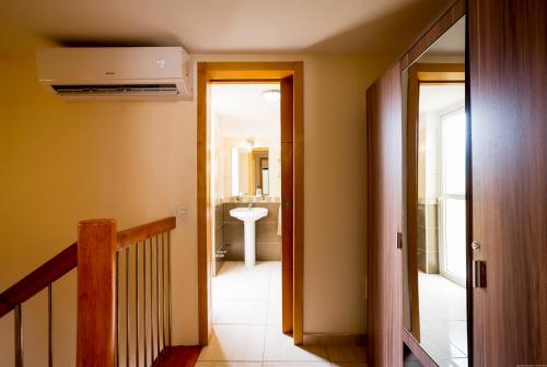 - un couloir avec une salle de bains pourvue d'un lavabo et d'un escalier dans l'établissement Apartamentos El Cortijo, à Playa de las Americas