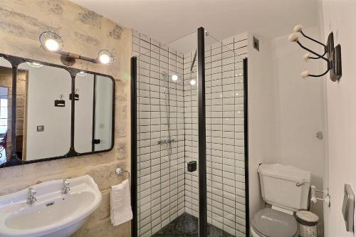 een badkamer met een wastafel, een toilet en een spiegel bij DUPLEX CENTRE HISTORIQUE UZES in Uzès