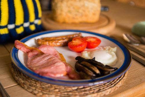a plate of food with bacon eggs sausage and tomatoes at Huntlands Farm Bed & Breakfast in Bromyard