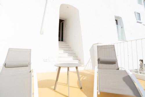 a white chair and stool on a balcony with a staircase at A casa di Dany in Polignano a Mare