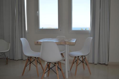 a dining room with a table and white chairs at Faros Resort in Azolimnos
