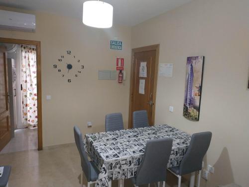 a dining room with a table and chairs and a clock on the wall at Caciris in Cáceres