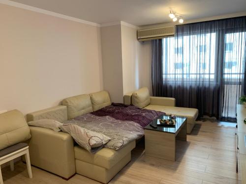 a living room with a couch and a table at Хепи Апартмънтс in Plovdiv