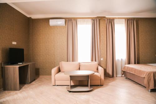 Habitación de hotel con silla, cama y TV en Old Gagra Hotel, en Gagra