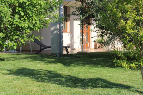a bench sitting in the grass next to a house at LE SETTE VIE HOLIDAY HOMES in Monforte dʼAlba