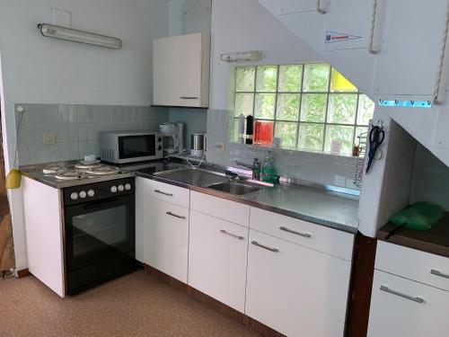 a kitchen with white cabinets and a sink and a microwave at Casi in Brienz