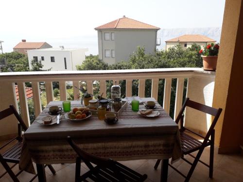 a table on a balcony with food on it at Apartments Jadranka Povile in Novi Vinodolski