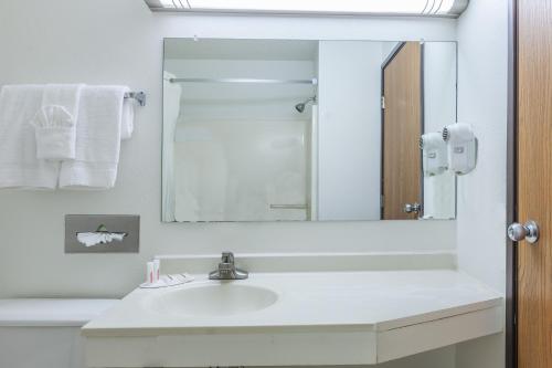 a white bathroom with a sink and a mirror at Super 8 by Wyndham Irving DFW Airport/South in Irving