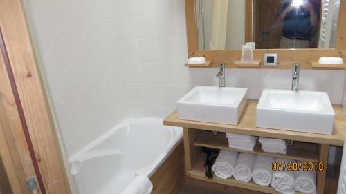 une salle de bain avec deux lavabos et une baignoire dans l'établissement Alpine Lodge 9, aux Contamines-Montjoie