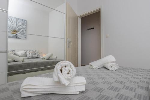 a room with a bed with towels and a mirror at Apartments Ankica in Crikvenica