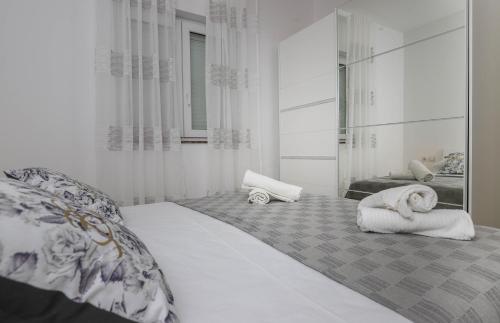 a white bedroom with a bed with towels on it at Apartments Ankica in Crikvenica