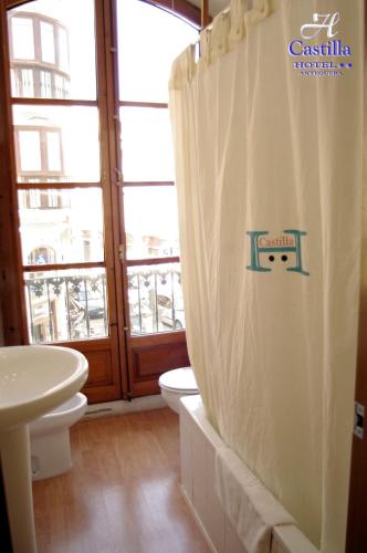 a bathroom with a toilet and a shower curtain at Hotel Castilla in Antequera