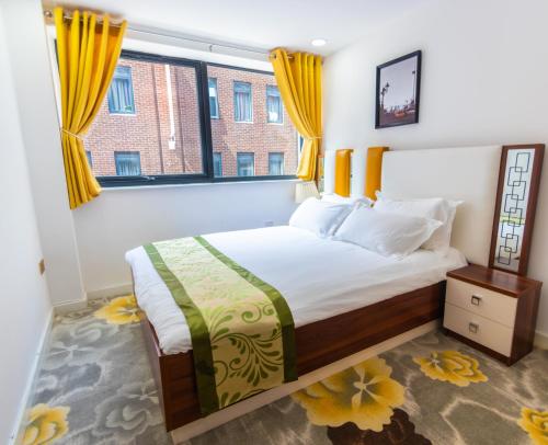 a bedroom with a large bed with yellow curtains at Queen Stay Apartments in Sheffield