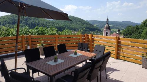 a wooden table with chairs and an umbrella on a balcony at Bílá hora Štramberk in Štramberk