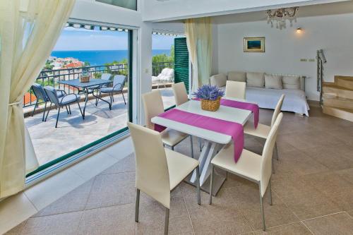 a dining room with a table and chairs and a balcony at Island Hvar Seaside Villa Levanda with Beach, Pool & Seaview in Hvar