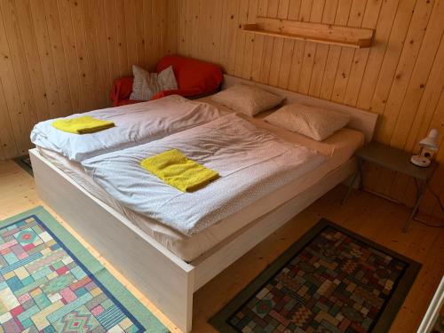 Bett in einem Holzzimmer mit gelben Kissen darauf in der Unterkunft Chata u Zámku in Stráž nad Nežárkou