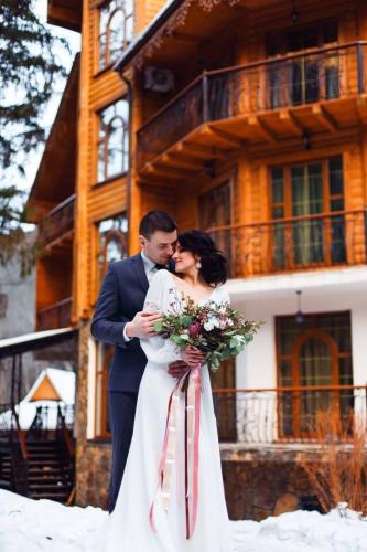 a bride and groom kissing in front of a building at Hotel Dykyi Med in Tatariv