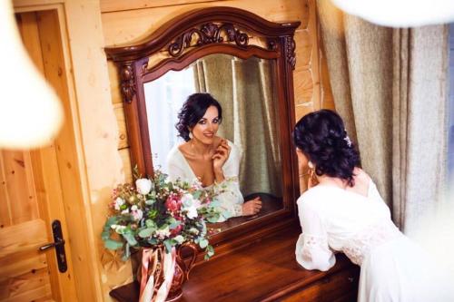 a bride looking at herself in a mirror at Hotel Dykyi Med in Tatariv