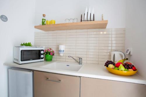 a kitchen counter with a microwave and a bowl of fruit at Kibbutz Malkiya Travel Hotel in Malkiyya