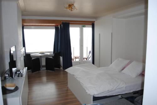 a bedroom with a bed and a desk and a window at De Zee in Ostend