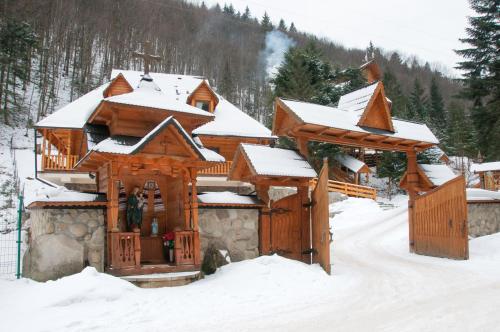 a log cabin with snow on the roof at Hotel Dykyi Med in Tatariv