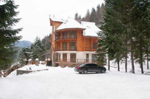 a car parked in front of a house in the snow at Hotel Dykyi Med in Tatariv