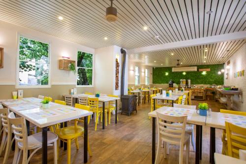 a restaurant with white tables and yellow chairs at Kibbutz Malkiya Travel Hotel in Malkiyya