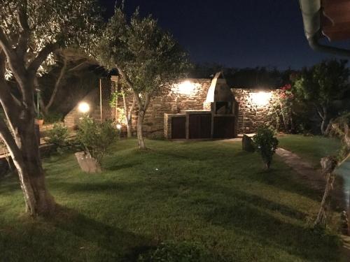 un jardin la nuit avec des lumières sur un bâtiment en pierre dans l'établissement Stintino casa con giardino vicino la Pelosa, à Stintino