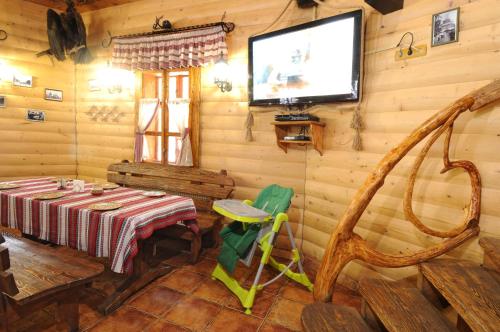 a dining room with a table and a tv on the wall at Hotel Dykyi Med in Tatariv