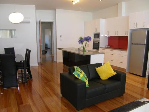 a living room with a couch and a kitchen at Penguin Waterfront Escape in Penguin