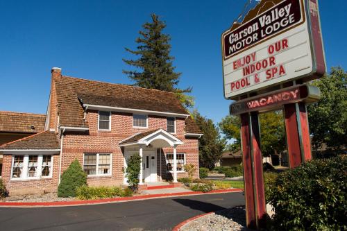 a sign in front of a brick building with a house at Carson Valley Motor Lodge and Suites in Minden