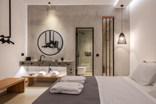 a bedroom with a bed and a bathroom with a sink at Avra Mykonos in Tourlos