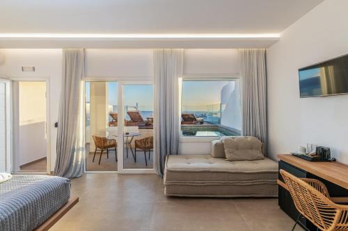 a bedroom with a bed and a couch and a balcony at Avra Mykonos in Tourlos