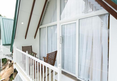 a screened porch with white curtains and rocking chairs at Orchid Villa Kandy in Kandy