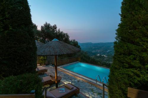 ein Pool mit Sonnenschirm und Stühlen daneben in der Unterkunft Villa Kastelas in Kato Asites