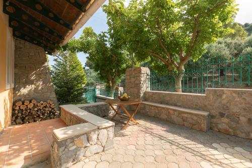 a patio with a table and a bench and trees at Villa Kastelas in Kato Asites