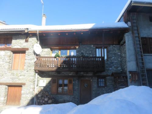 a stone house with a balcony and snow in front of it at Chalet Fr Gilkens Arc 1600 in Bourg-Saint-Maurice