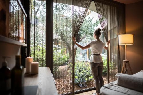 a woman standing in front of a window looking outside at SPA & Relax Hotel Erika in Tirolo