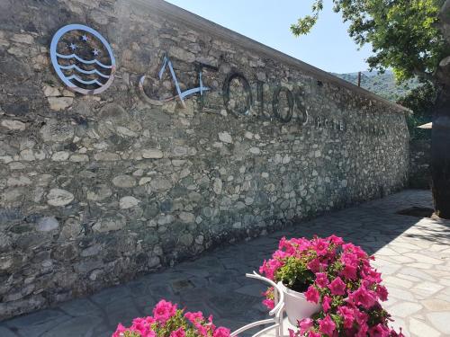 a sign on a stone wall with flowers in front at Aeolos Hotel & Villas - Pelion in Chorefto