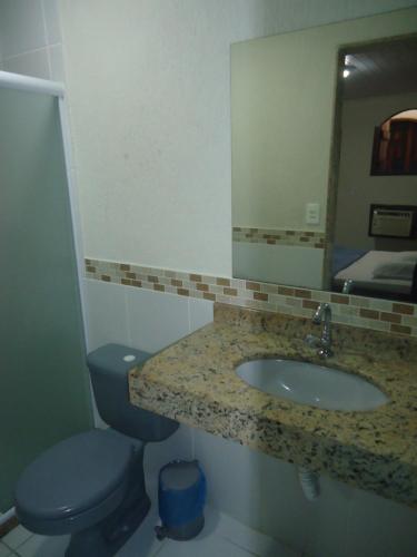 a bathroom with a sink and a toilet and a mirror at Pousada Vida Boa in Cabo Frio