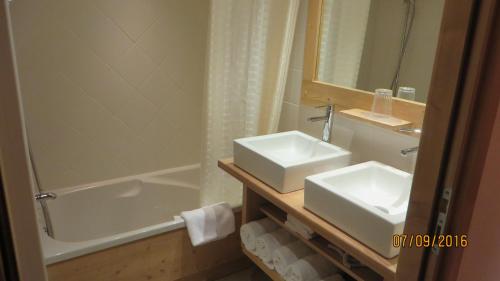 een badkamer met een wastafel, een bad en een spiegel bij Alpine Lodge 8 in Les Contamines-Montjoie