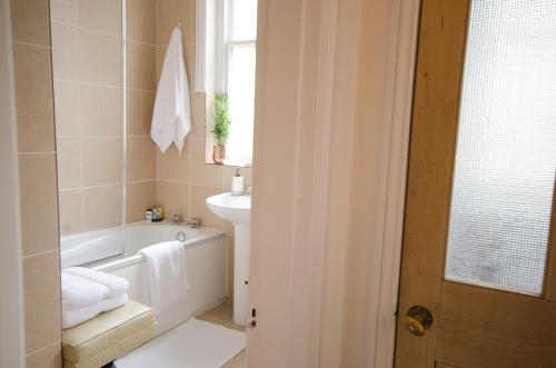 a bathroom with a white tub and a sink and a bath tub at Seaview Mansion Apartment - Central Hove with PARKING in Brighton & Hove