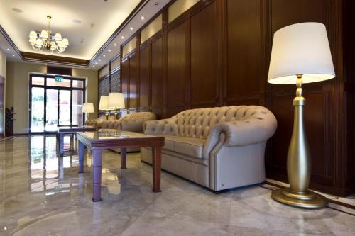 a living room with a couch and a table and a lamp at Centrum Hotel in Debrecen