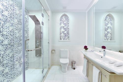 a white bathroom with a shower and a toilet at Hotelux La Playa Alamein in El Alamein