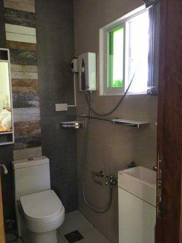a bathroom with a toilet and a sink and a window at Homaja Roomrental in Panglao Island