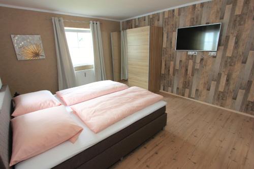 a bedroom with a bed with pink pillows and a flat screen tv at Mama Roserl in Hauzenberg