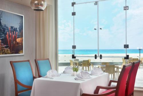 a dining room with a table and chairs with a view of the beach at Hotelux La Playa Alamein in El Alamein